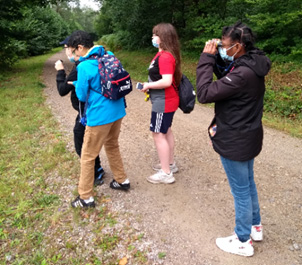 Während der Wanderung beobachten Yusuf, Majdi, Angelina und Celsa mit Fernglas und Monokular in der Ferne Pferde.